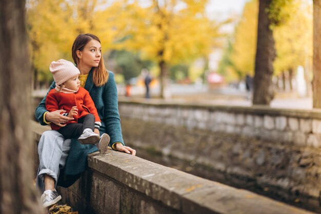 Madre joven con su pequeña hija en un parque de otoño