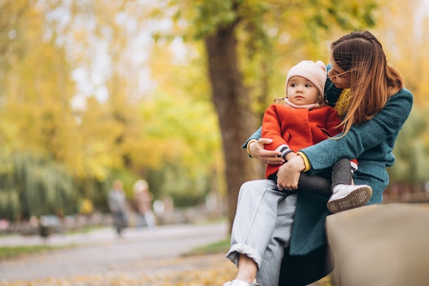 Madre joven con su pequeña hija en un parque de otoño