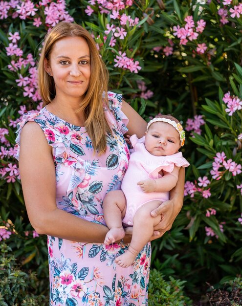 Madre joven con un vestido con flores sosteniendo a su pequeña niña