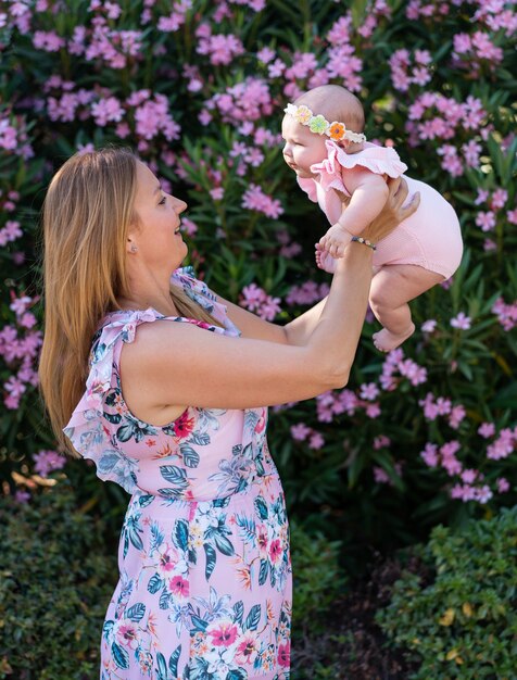 Madre joven con un vestido con flores sosteniendo a su pequeña niña