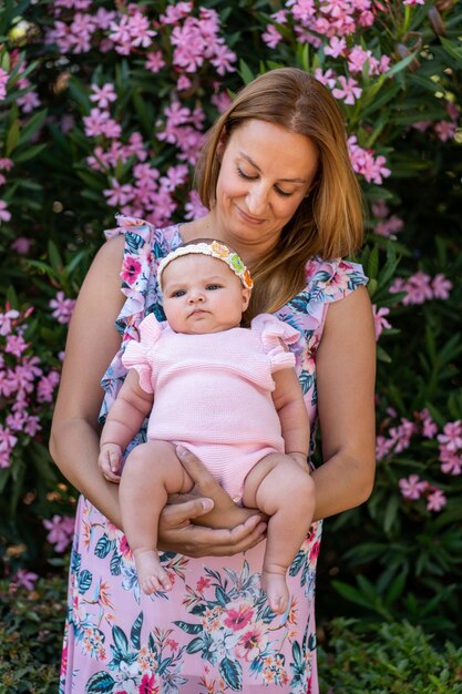 Madre joven con un vestido con flores sosteniendo a su pequeña niña