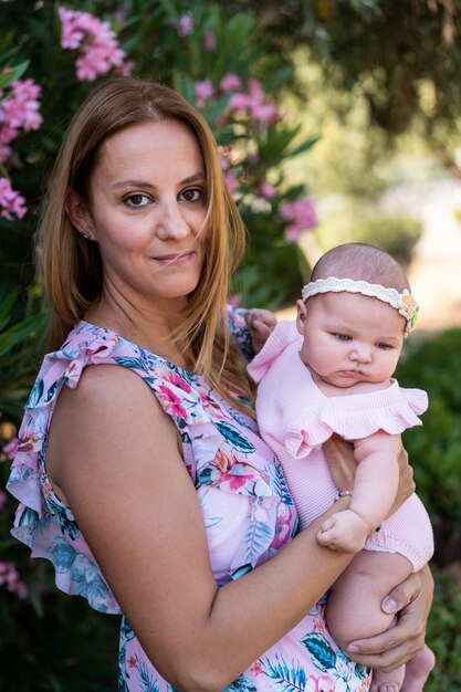 Madre joven con un vestido con flores sosteniendo a su pequeña niña