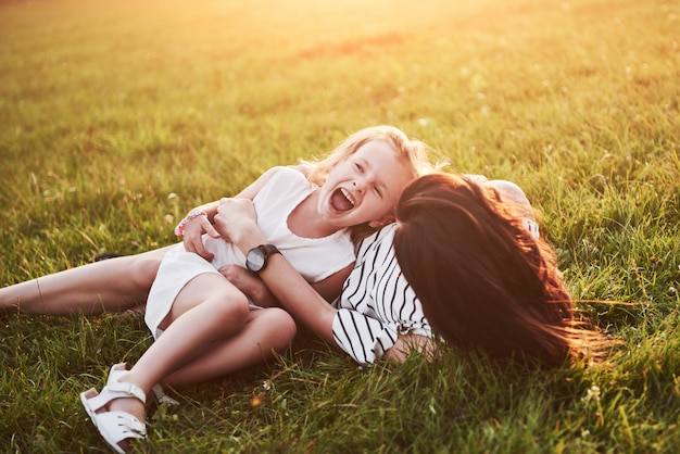 Madre juega con su hija en la calle en el parque al atardecer