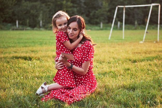 Madre juega con su hija en la calle en el parque al atardecer