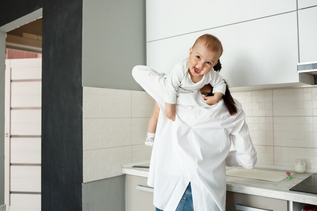 Madre jugando con el bebé en la cocina