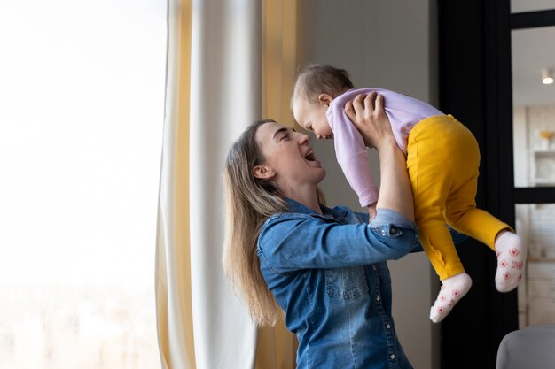 Madre jugando con su bebé mientras lo levanta y lo hace reír