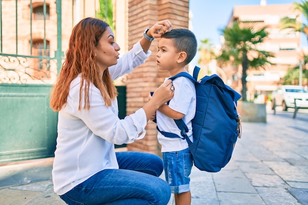 Foto gratuita madre latina peinando con la mano a su estudiante en la ciudad.