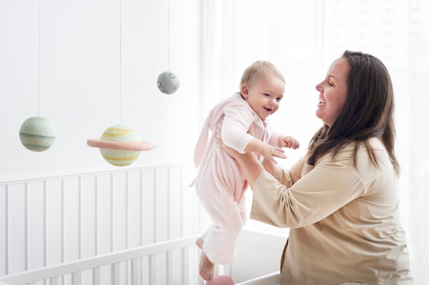 Foto gratuita madre levantando a su bebé de su cuna