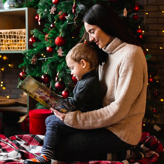 Foto gratuita madre leyendo cuento de navidad a su hijo