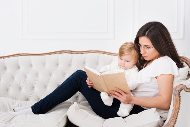 Madre leyendo en el sofá con bebé