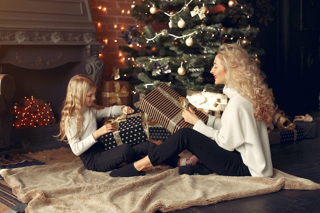 Madre con linda hija en casa cerca del árbol de Navidad