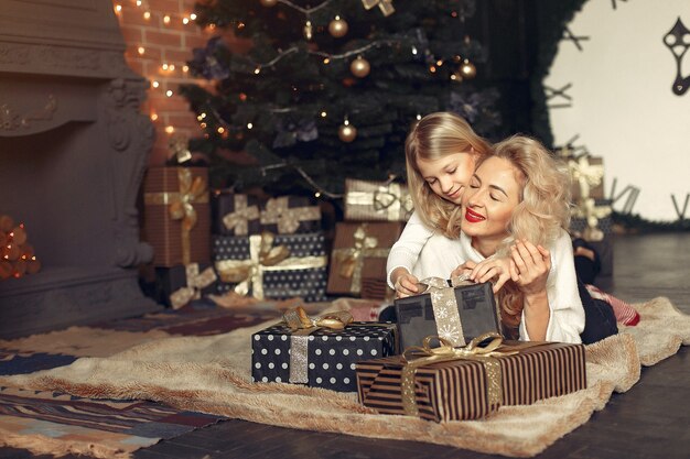 Madre con linda hija en casa cerca del árbol de Navidad