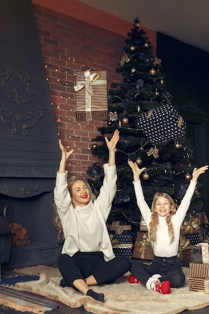 Madre con linda hija en casa cerca del árbol de Navidad