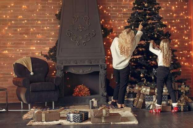 Madre con linda hija en casa cerca del árbol de Navidad