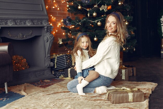 Madre con linda hija en casa junto a la chimenea