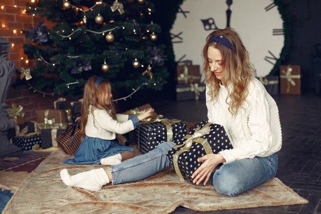 Madre con linda hija en casa junto a la chimenea