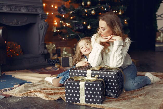 Madre con linda hija en casa junto a la chimenea