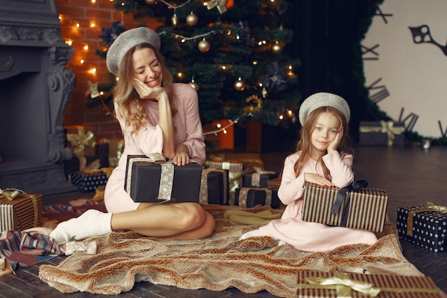 Madre con linda hija en casa junto a la chimenea