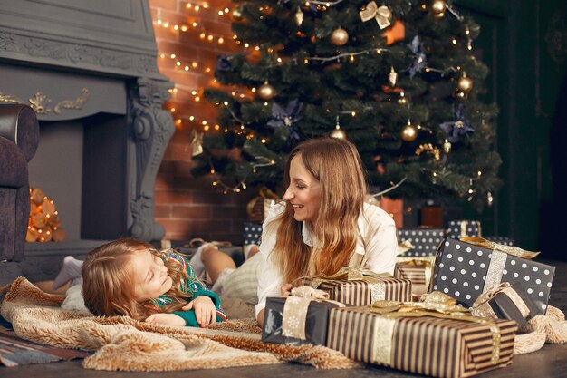 Madre con linda hija en casa junto a la chimenea