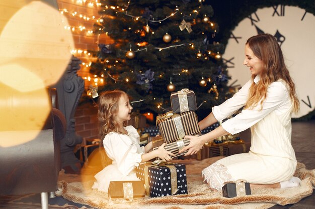 Madre con linda hija en casa junto a la chimenea