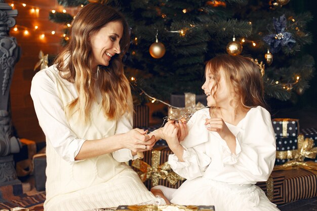 Madre con linda hija en casa junto a la chimenea