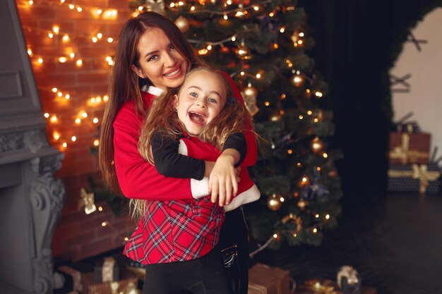 Madre con linda hija en casa junto a la chimenea