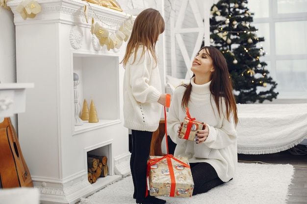 Madre con linda hija en casa con regalos de navidad