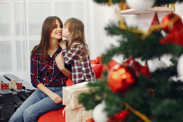 Madre con linda hija en casa con regalos de navidad