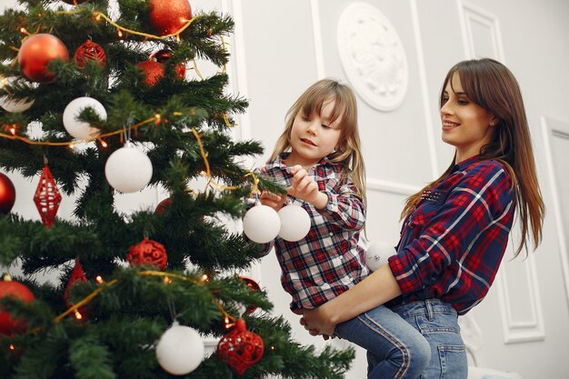 Madre con linda hija en casa con regalos de navidad