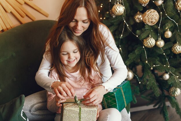 Madre con linda hija cerca del árbol de Navidad