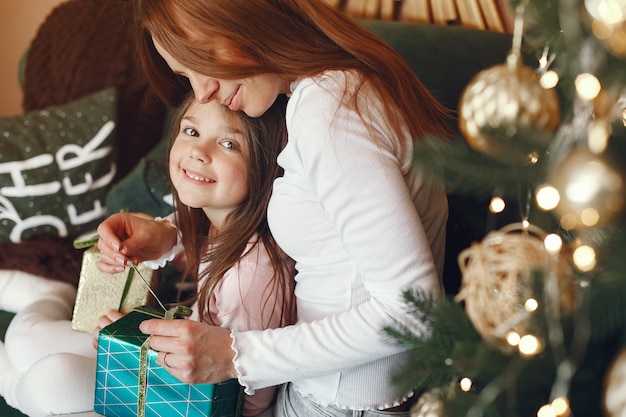 Madre con linda hija cerca del árbol de Navidad