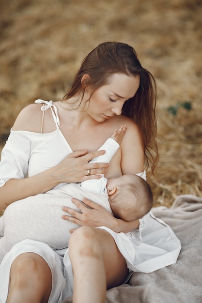 Madre con linda hija. Mamá amamantando a su pequeña hija. Mujer con un vestido blanco.