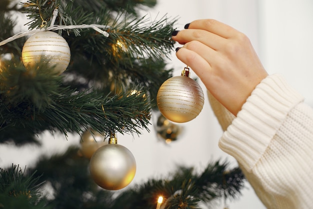 Madre con linda hija de pie cerca del árbol de navidad