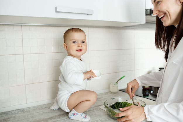 Madre con lindo bebé cocinando en la cocina