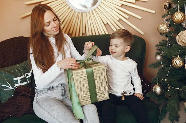 Madre con lindo hijo cerca del árbol de navidad