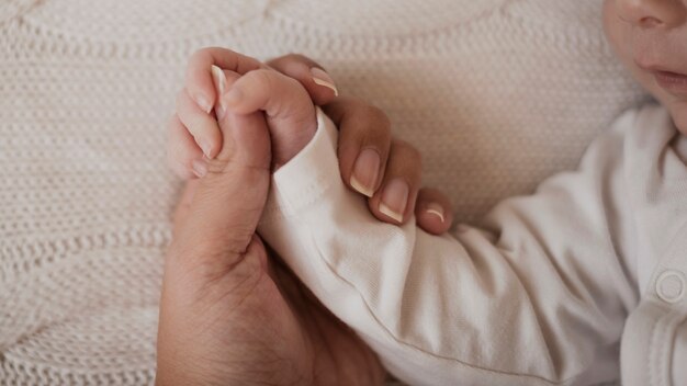 Madre mano que sostiene el pequeño brazo del bebé