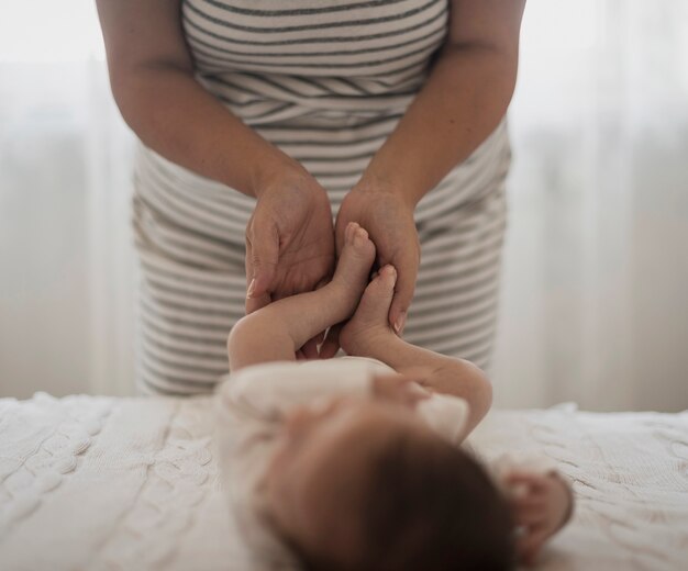 Madre manos jugando con piernas de bebé