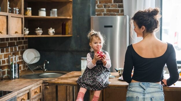 Madre mirando a la niña con manzana