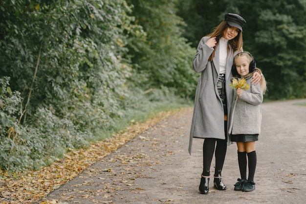 Madre de moda con hija. La gente camina afuera. Mujer con un abrigo gris.