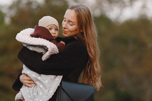 Madre de moda con hija. La gente camina afuera. Mujer con chaqueta negra.