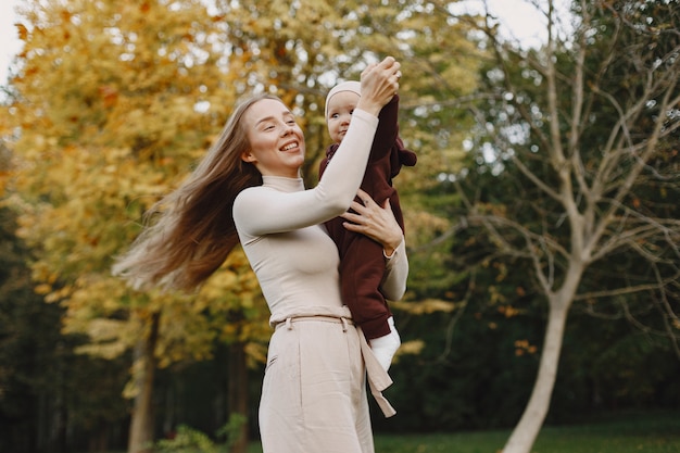 Madre de moda con hija. La gente camina afuera. Mujer con un suéter marrón.