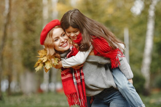 Madre de moda con hija. Otoño amarillo. Mujer con pañuelo rojo.