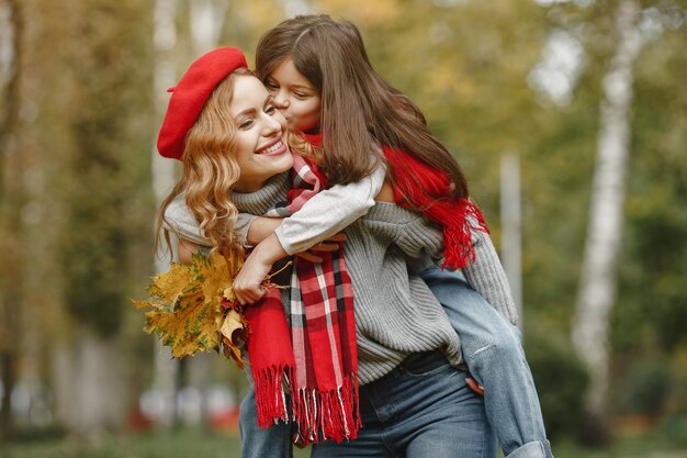 Madre de moda con hija. Otoño amarillo. Mujer con pañuelo rojo.