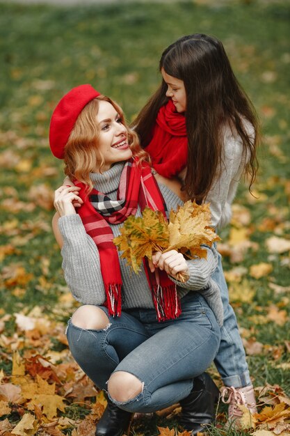 Madre de moda con hija. Otoño amarillo. Mujer con pañuelo rojo.