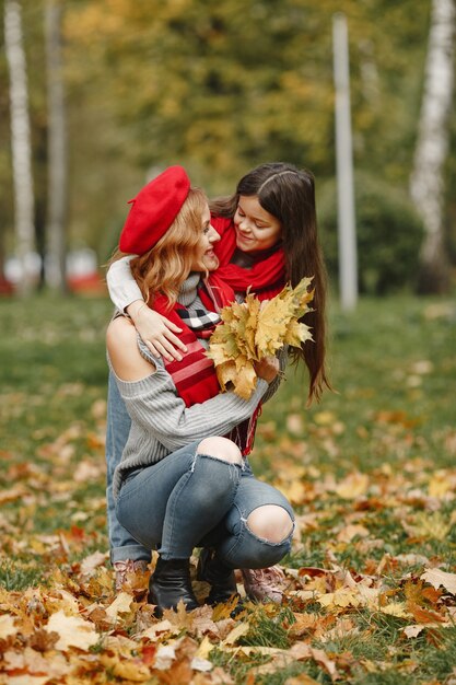 Madre de moda con hija. Otoño amarillo. Mujer con pañuelo rojo.