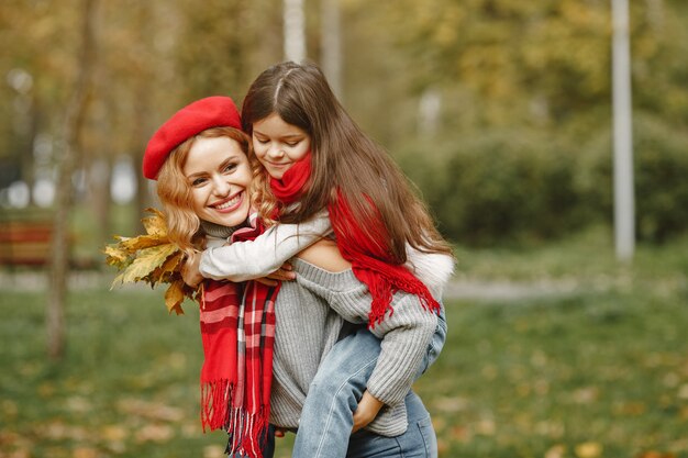 Madre de moda con hija. Otoño amarillo. Mujer con pañuelo rojo.