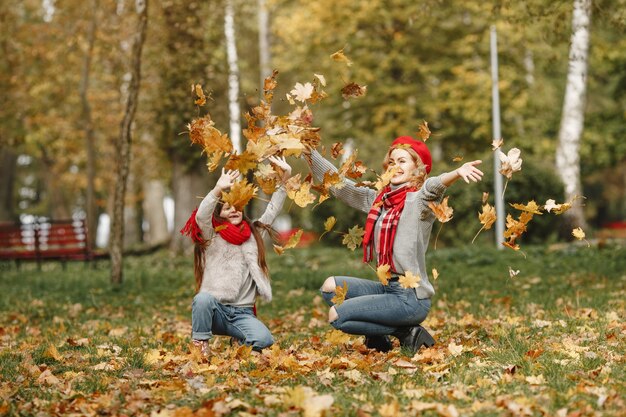 Madre de moda con hija. Otoño amarillo. Mujer con pañuelo rojo.