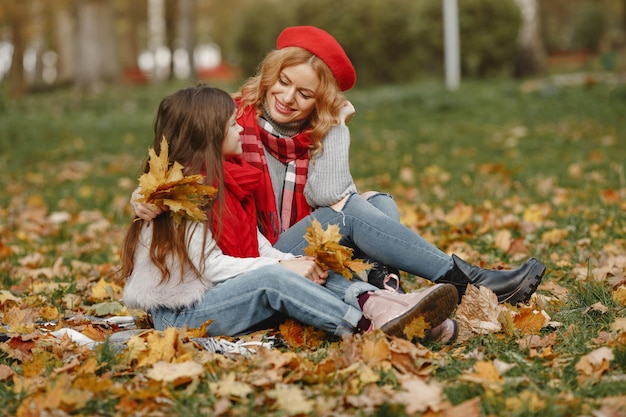 Madre de moda con hija. Otoño amarillo. Mujer con pañuelo rojo.