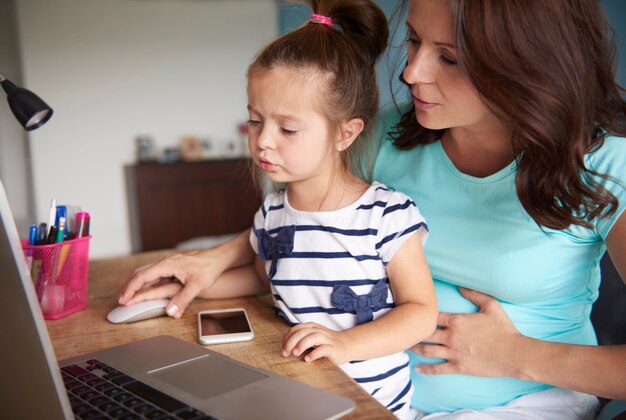 Madre mostrando a su hija cómo usar la computadora