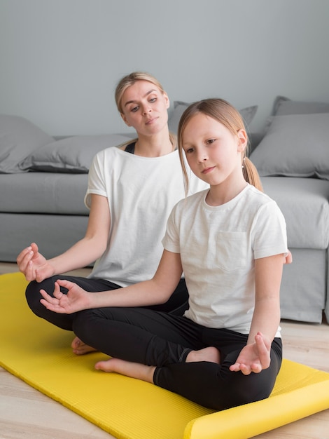 Madre y niña en casa practicando yoga